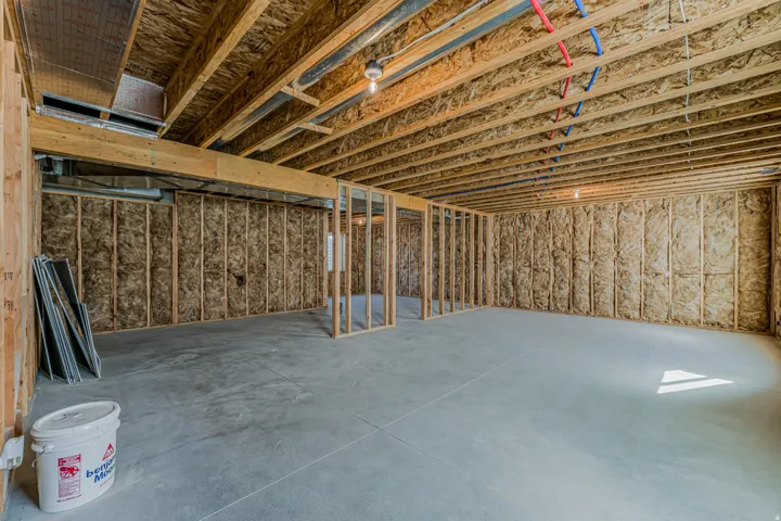 Unfinished basement featuring wood framing, insulation, concrete flooring, and exposed ceiling joists