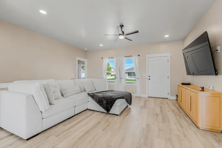 Recessed lighting, wood-finish flooring, ceiling fan, and white trim