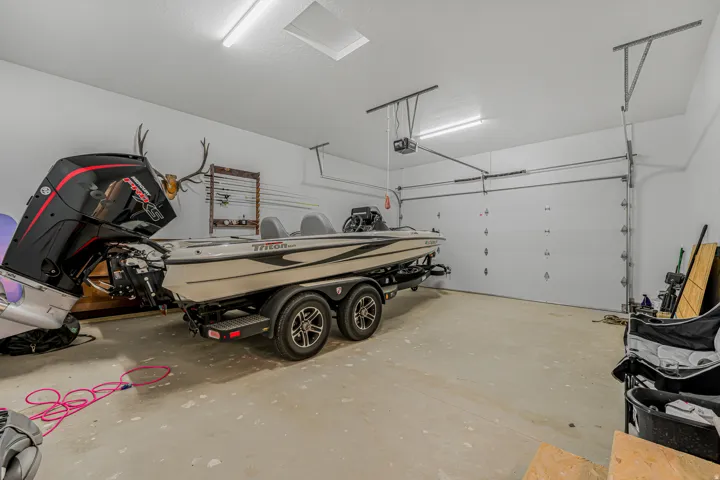 Spacious garage with an overhead door, smooth concrete flooring, and ceiling-mounted fluorescent lighting