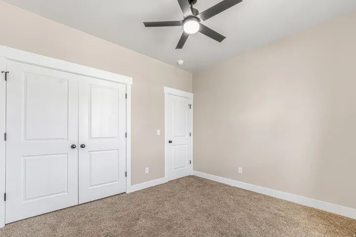Neutral wall paint, plush carpet flooring, ceiling fan with integrated lighting, white trim, and paneled doors