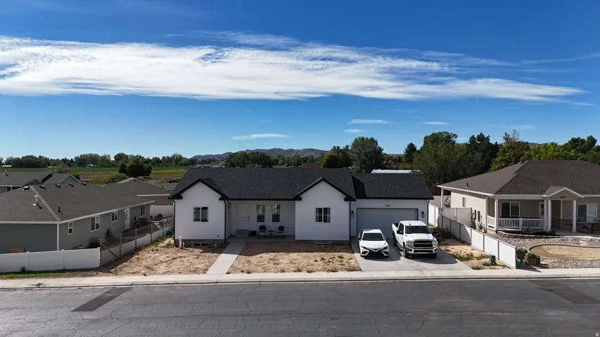 White siding exterior with a dark shingle roof, attached garage, and concrete driveway