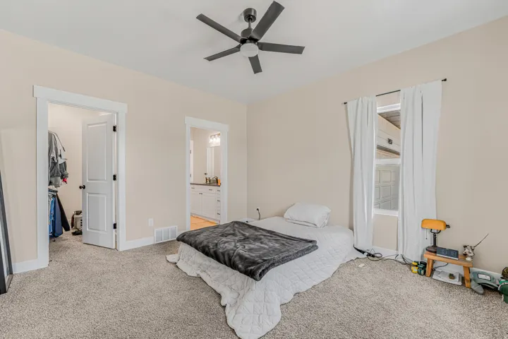 Carpeted room with a ceiling fan, a window with white curtains, and two interior doorways