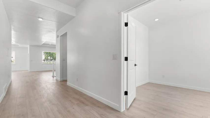 Light wood-finish flooring extends throughout, complemented by white walls and recessed ceiling lighting