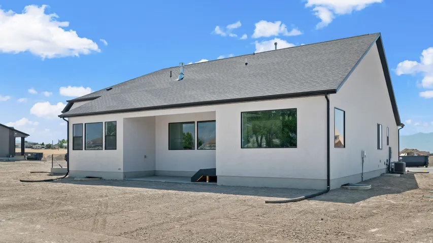White stucco exterior with black-framed windows, dark asphalt shingle roofing, and black gutters