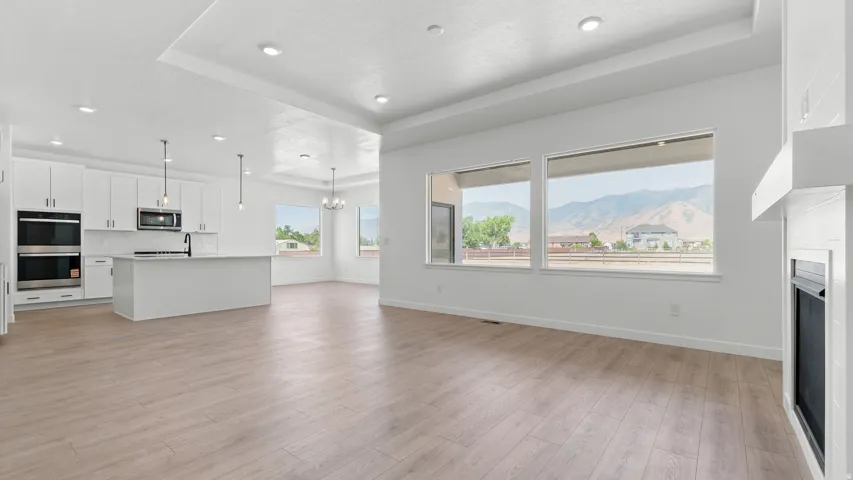 Open-concept living space featuring wood-finish flooring, a contemporary fireplace, and recessed lighting