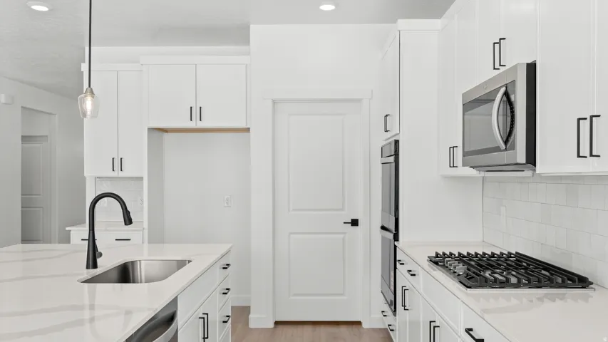 Kitchen featuring white cabinetry, stainless steel appliances, a gas cooktop, and a kitchen island with an undermount sink