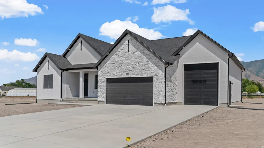 Contemporary home with a light-colored stucco and stone facade, dark-framed windows, and a dark shingle roof
