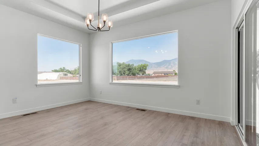 Recessed ceiling details, modern chandelier, large windows, wood-finish flooring, and a sliding glass door