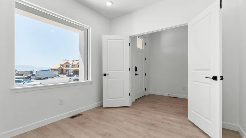 Spacious room featuring wood-finish flooring, white walls, and a large window