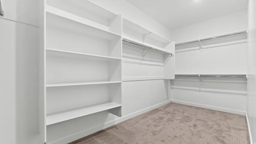 Built-in shelving, multiple hanging rods, and neutral carpeting