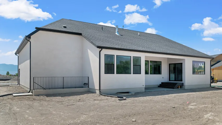White stucco exterior with black-framed windows, a covered patio, and a dark shingle roof