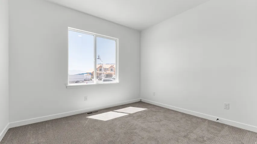 Expansive room featuring light gray carpeting and bright white walls