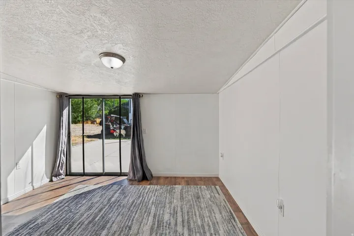 LVP Wood-finish Look  flooring, sliding glass doors, ceiling-mounted light fixture, and textured ceiling