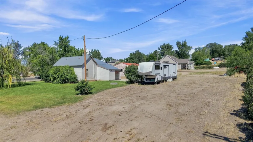 Expansive lot featuring a primary residence with a gray metal roof, mature trees, and a separate structure
