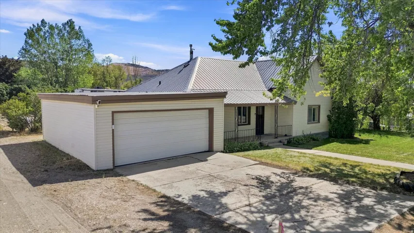 White siding exterior with a dark metal roof, featuring an attached garage with a white overhead door