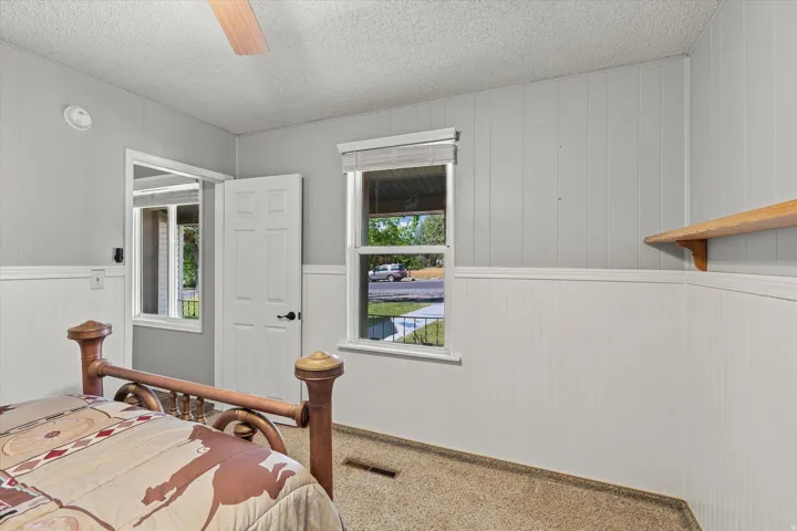 Wall paneling, built-in shelving, ceiling fan, and carpet flooring