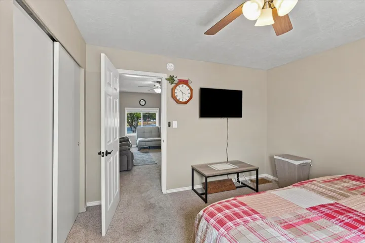 Carpeted flooring, ceiling fan with integrated lighting, and a paneled interior door with dark hardware
