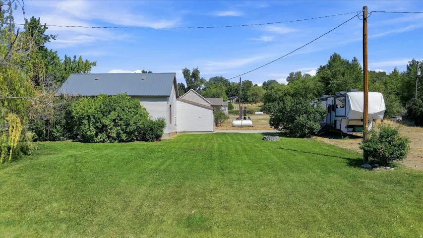 Expansive green lawn with mature trees and a detached structure featuring a metal roof