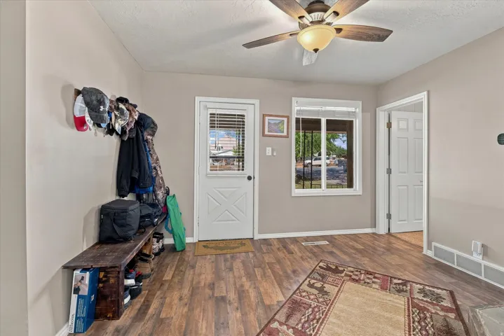 Wood-finish flooring, ceiling fan with integrated lighting, white-framed window, and white interior door