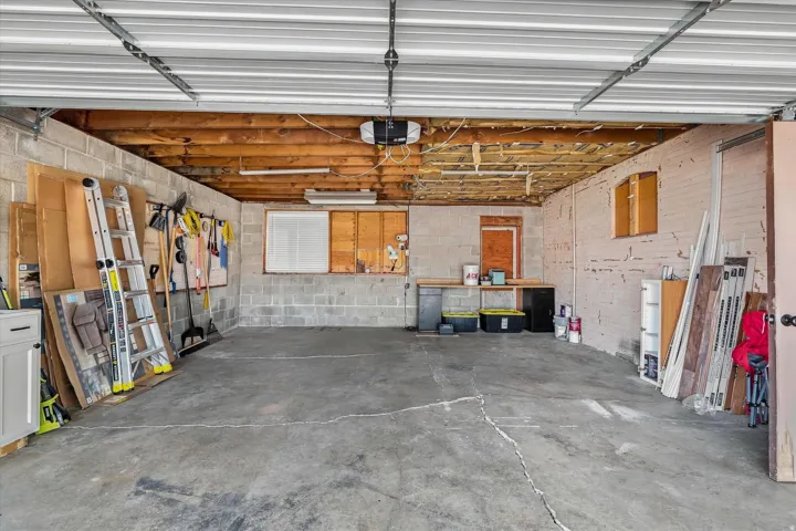 Garage featuring exposed wood beam ceiling, concrete block walls, and integrated workbench