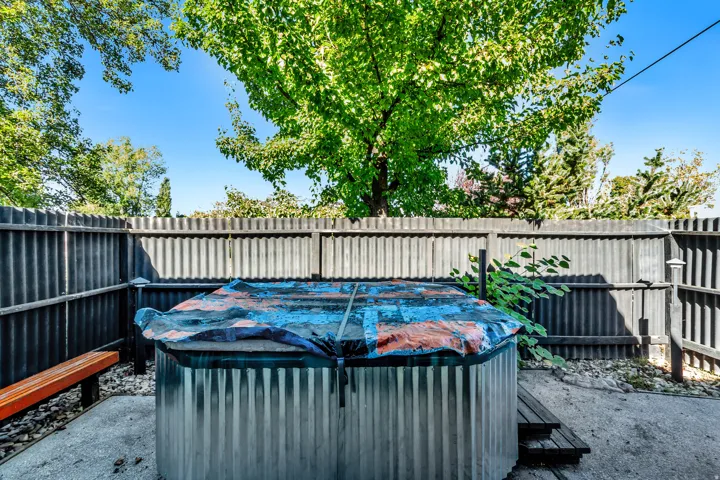 Corrugated metal fencing enclosing an outdoor area with a covered spa