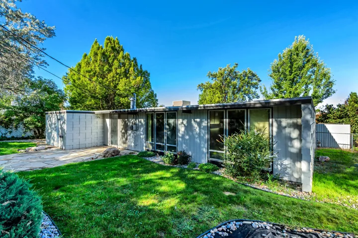 Single-story exterior with a flat roofline, floor-to-ceiling windows, and a stone slab patio
