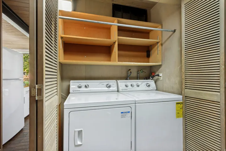 Built-in laundry appliances with an overhead storage cabinet and hanging rod