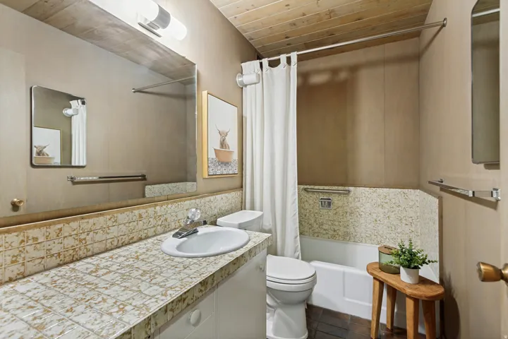 Bathroom featuring a wood-panel ceiling, tiled vanity with integrated sink, and a bathtub with a tiled surround