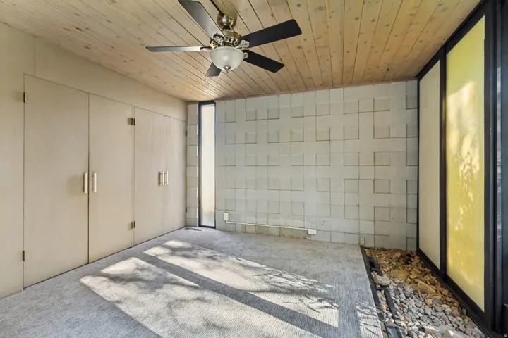 Wood-paneled ceiling with a ceiling fan, wall-to-wall carpeting, and a built-in storage system
