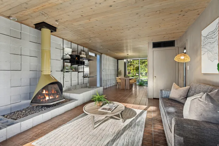 Wood-paneled ceiling, terracotta-style flooring, and a unique conical fireplace with a stone bed
