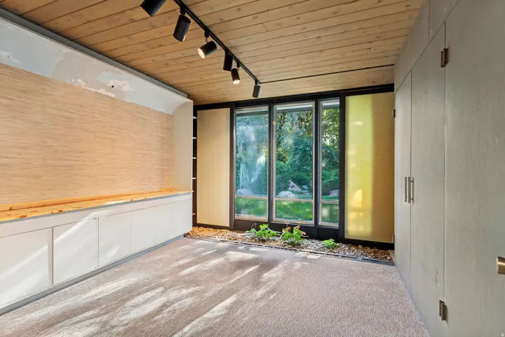 Wood-finish ceiling with track lighting, full-height windows, built-in cabinetry, and integrated rock garden