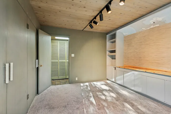 Wood-paneled ceiling with track lighting, built-in shelving, integrated cabinetry, and wood-finish countertop