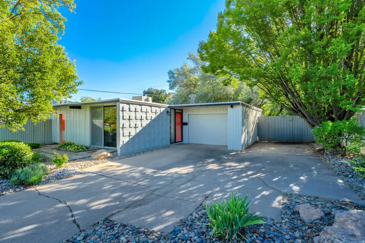 Mid-century modern exterior featuring a flat roofline, floor-to-ceiling windows, an attached garage, and a concrete driveway
