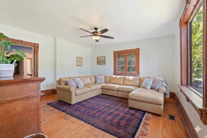 Hardwood flooring, wood trim around windows, wood trim around doorway, ceiling fan with light fixture