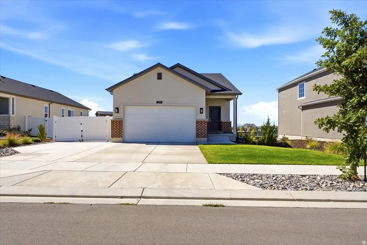 Stucco exterior with brick accents, attached garage, concrete driveway, front porch, and manicured lawn