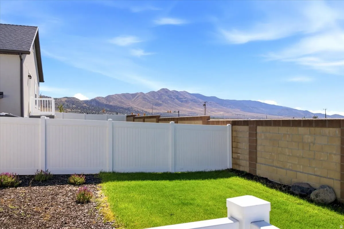 Expansive backyard featuring a manicured lawn, a white privacy fence, and a decorative block wall