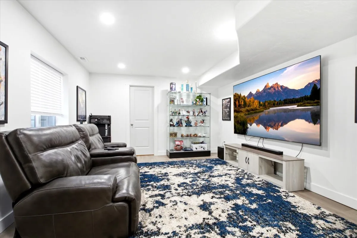 Recessed lighting illuminates the white walls and light wood-finish flooring
