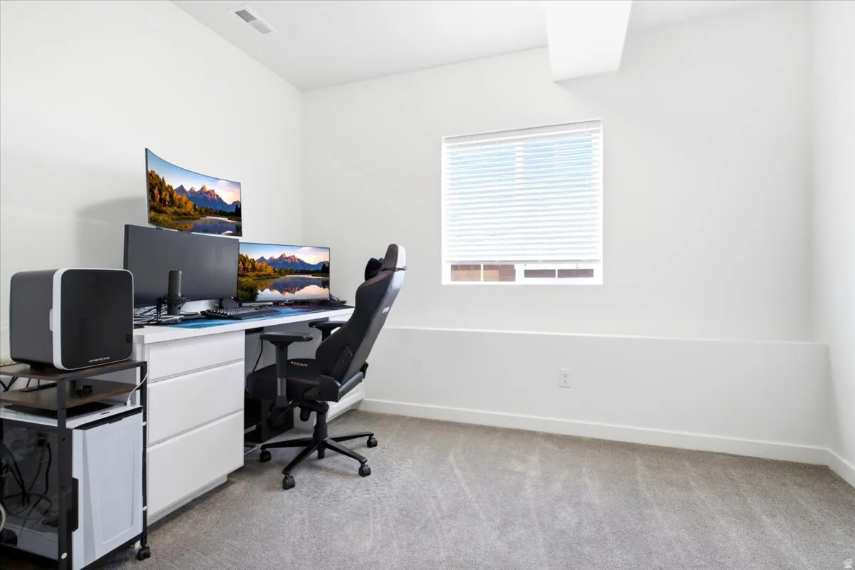 Bright interior space with carpet flooring and a window with blinds