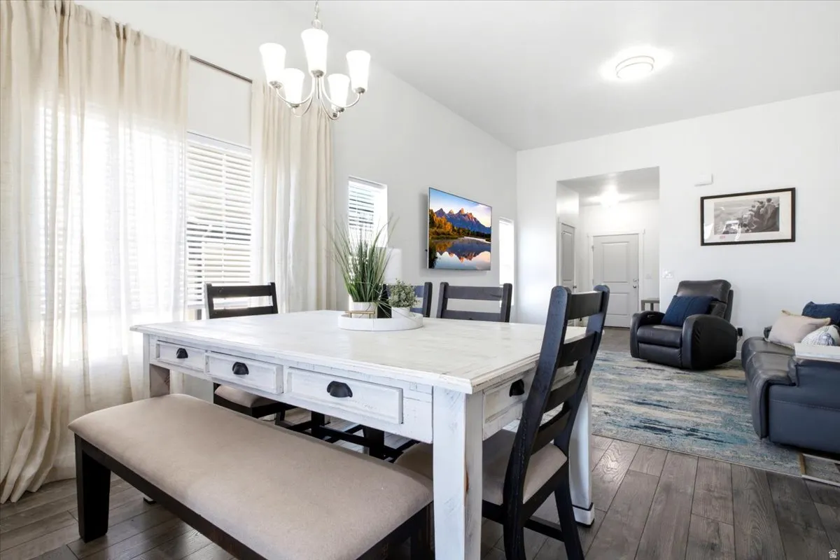 Vaulted ceiling with a chandelier, wood-finish flooring, and white interior walls
