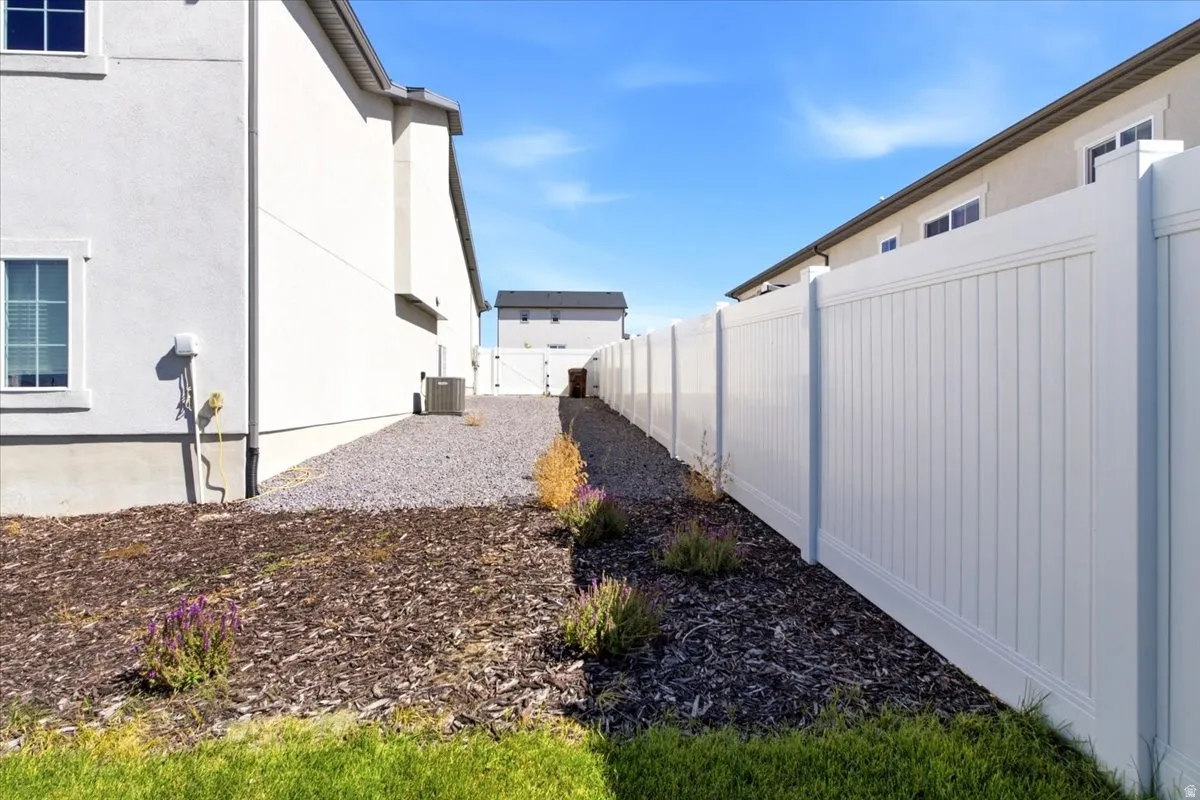 White vinyl privacy fence, gravel pathway, and stucco exterior