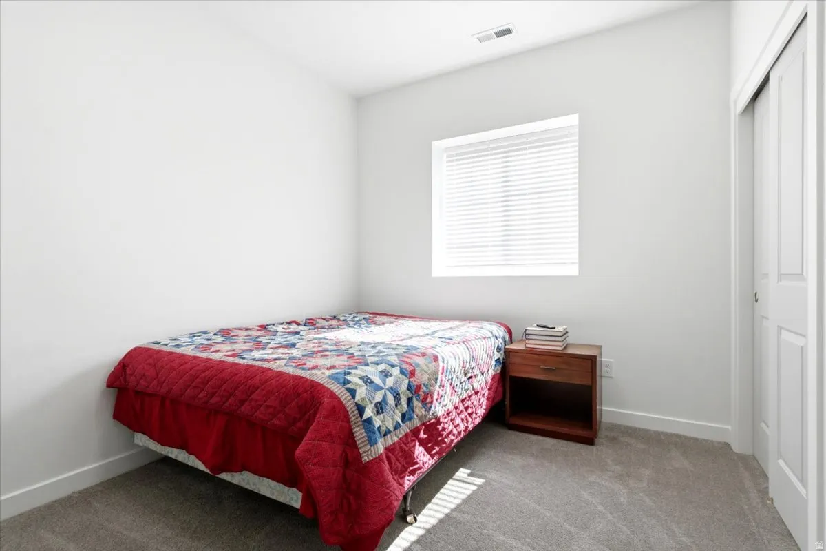 Neutral wall paint, window with blinds, gray carpeting, and sliding closet door