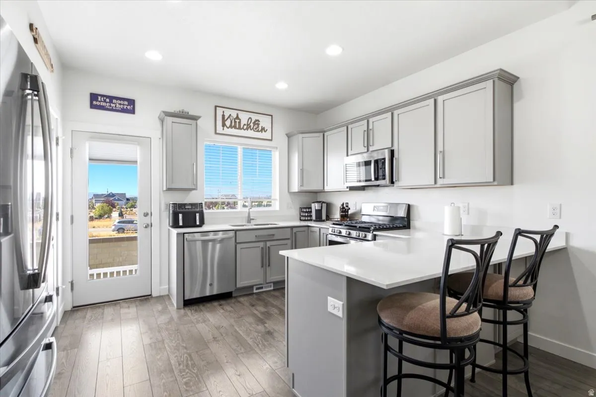 White countertops, stainless steel appliances, grey cabinetry, and a full-light door