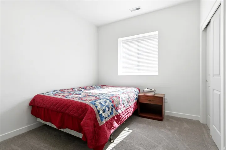 Neutral wall paint, window with blinds, gray carpeting, and sliding closet door