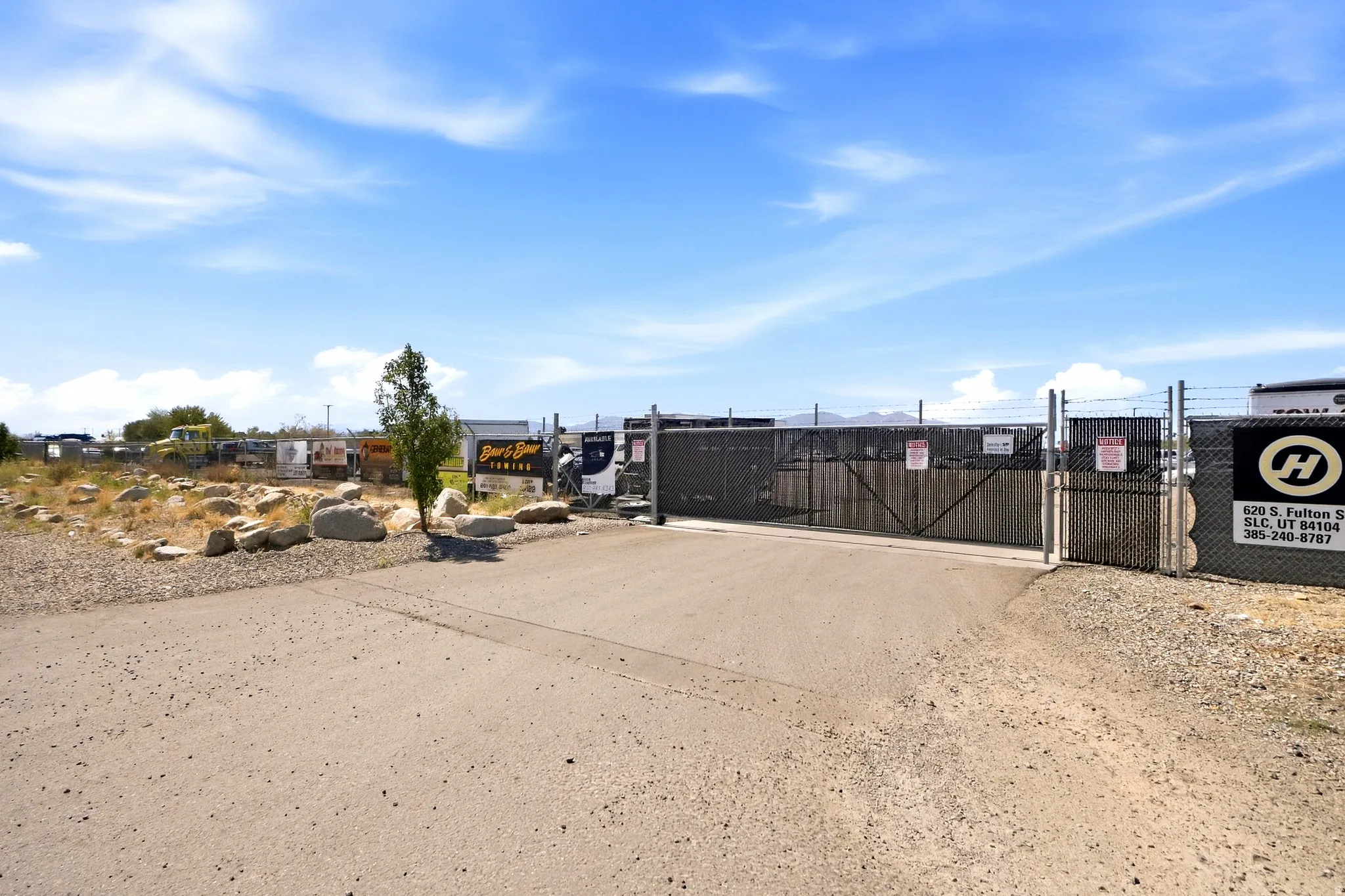 Paved lot entry with security fencing and a double gate