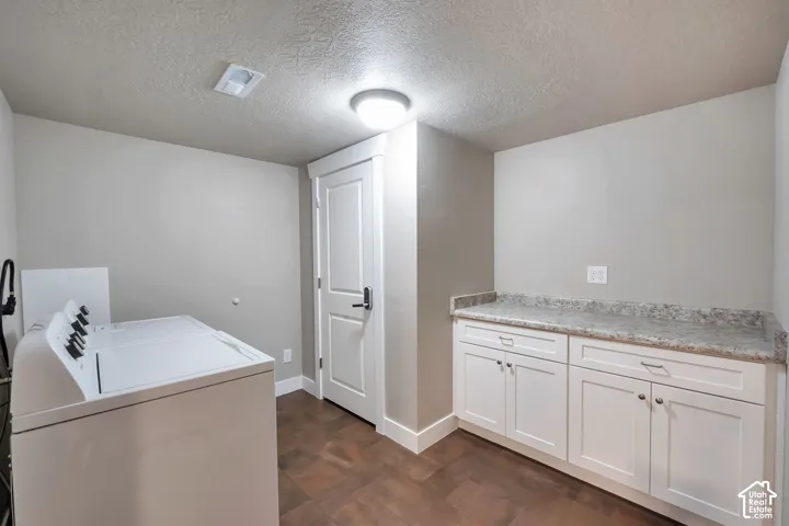 Built-in cabinetry with white shaker-style doors, stone-finish countertop, and dark wood-finish flooring