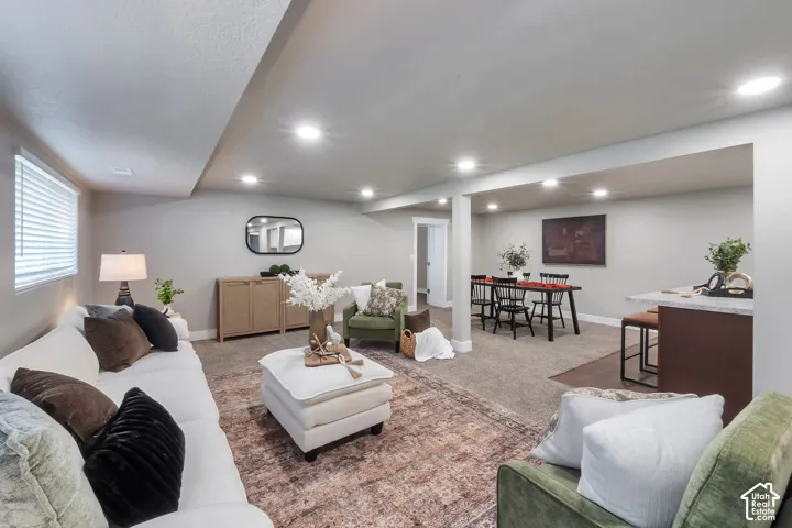 Recessed lighting illuminates the open-concept living space with carpet flooring