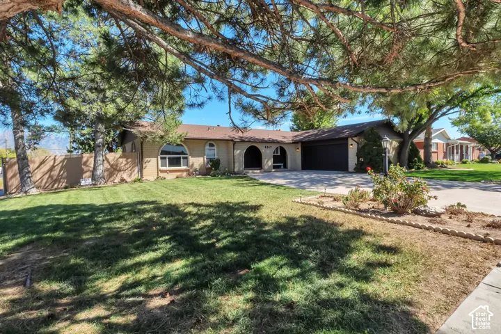 Single-story residence featuring a two-car garage, arched entryways, and a manicured front lawn