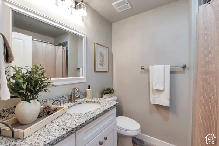 Bathroom featuring a vanity with granite-finish countertop, integrated sink, and brushed nickel faucet