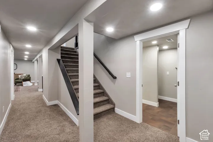 Carpeted flooring, recessed lighting, white trim, wood-finish flooring, and a carpeted staircase with a dark handrail
