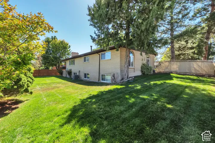 Expansive rear yard featuring mature trees, a privacy fence, and a brick exterior